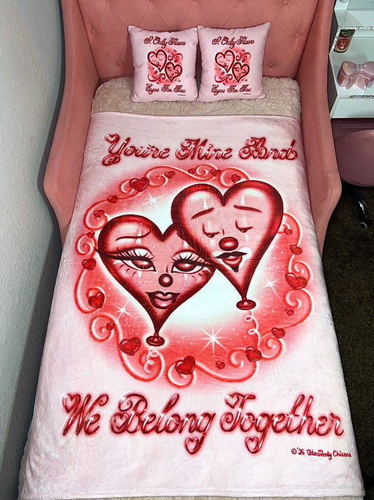 Bedding set with heart design and text 'You're Mine And We Belong Together' on a pink bed.